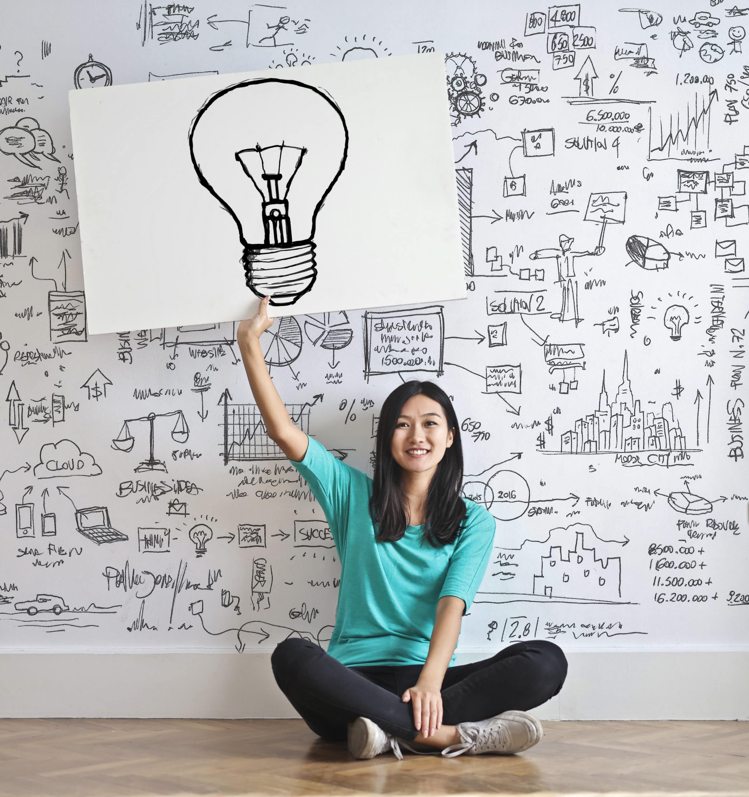 Woman thinking of an idea and holding a poster of a light bulb to signify innovation